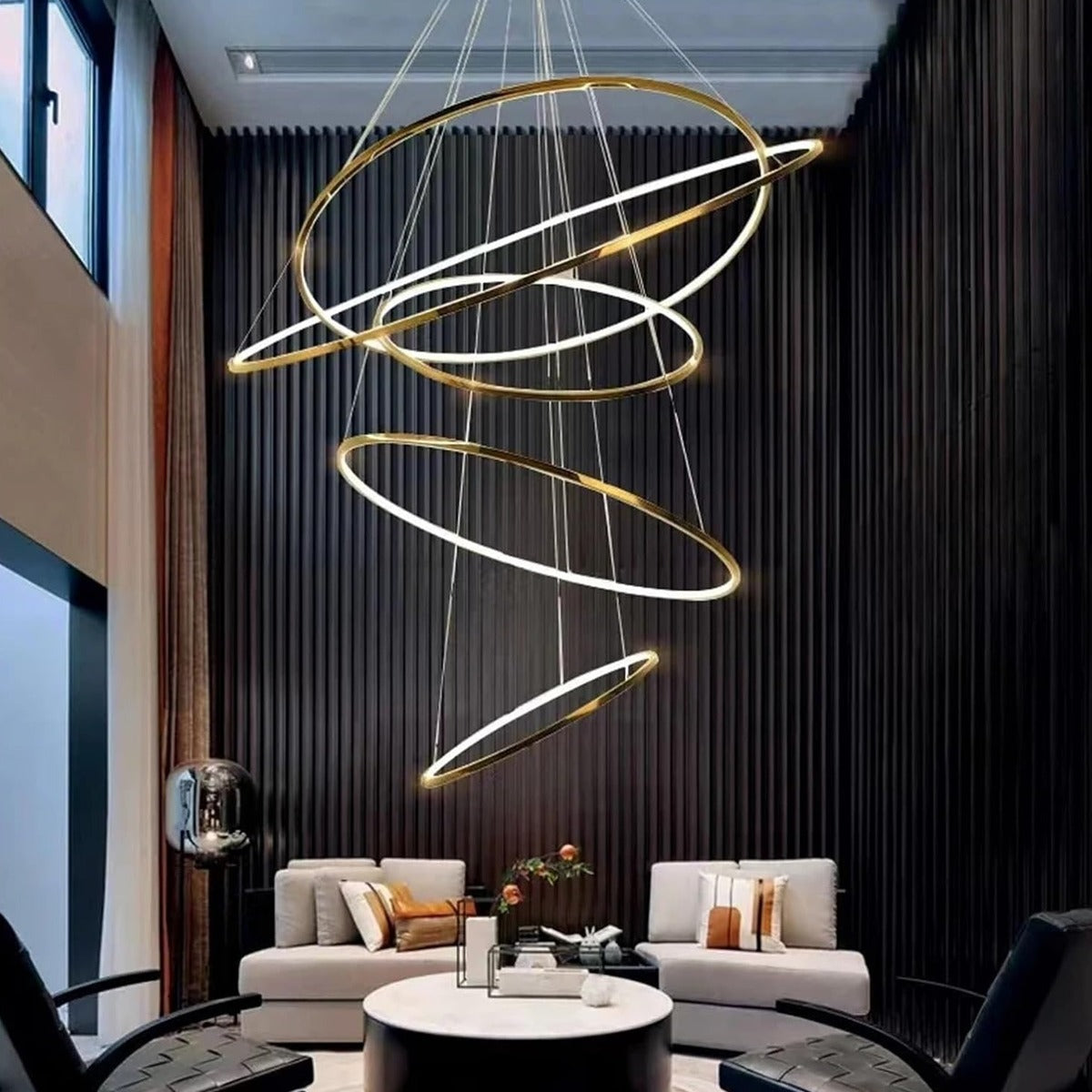 Gold Vela LED ring chandelier with 5 rings in a double-height living room