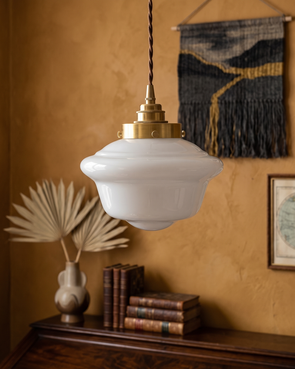 Elsie milk glass pendant light above a wood console with books
