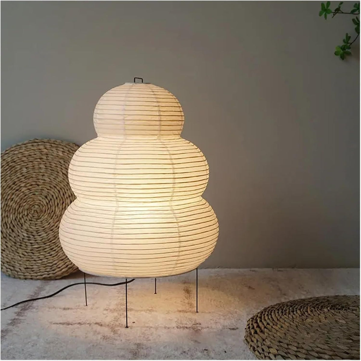 Kumo rice paper lantern lamp giving a warm glow beside woven cushions