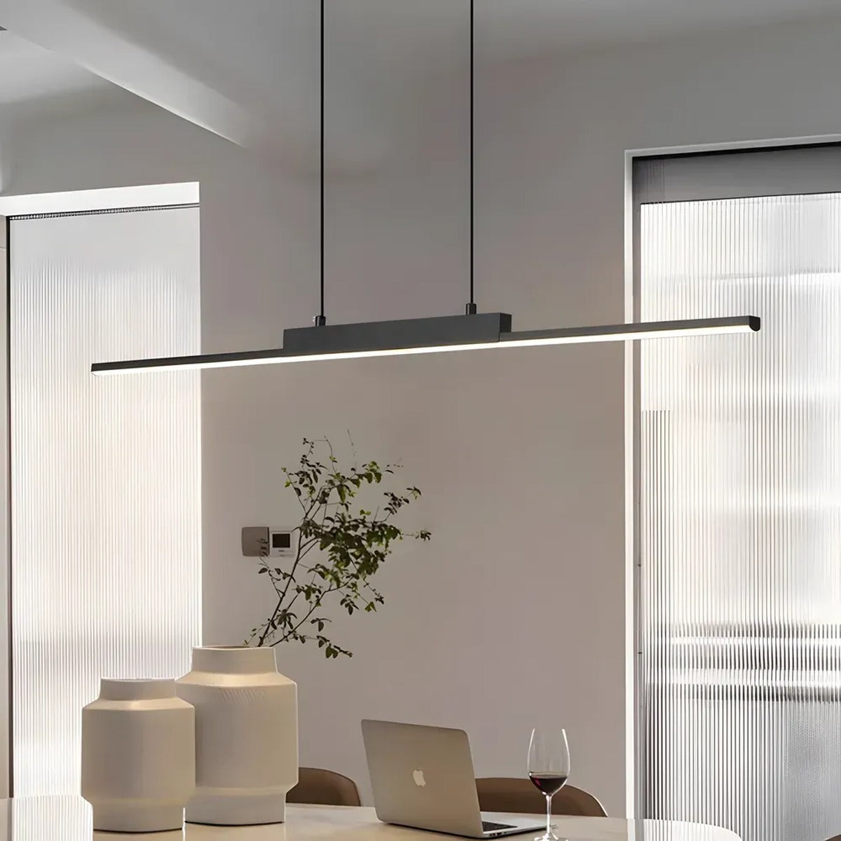 Elio linear LED pendant giving warm white light over a dining table