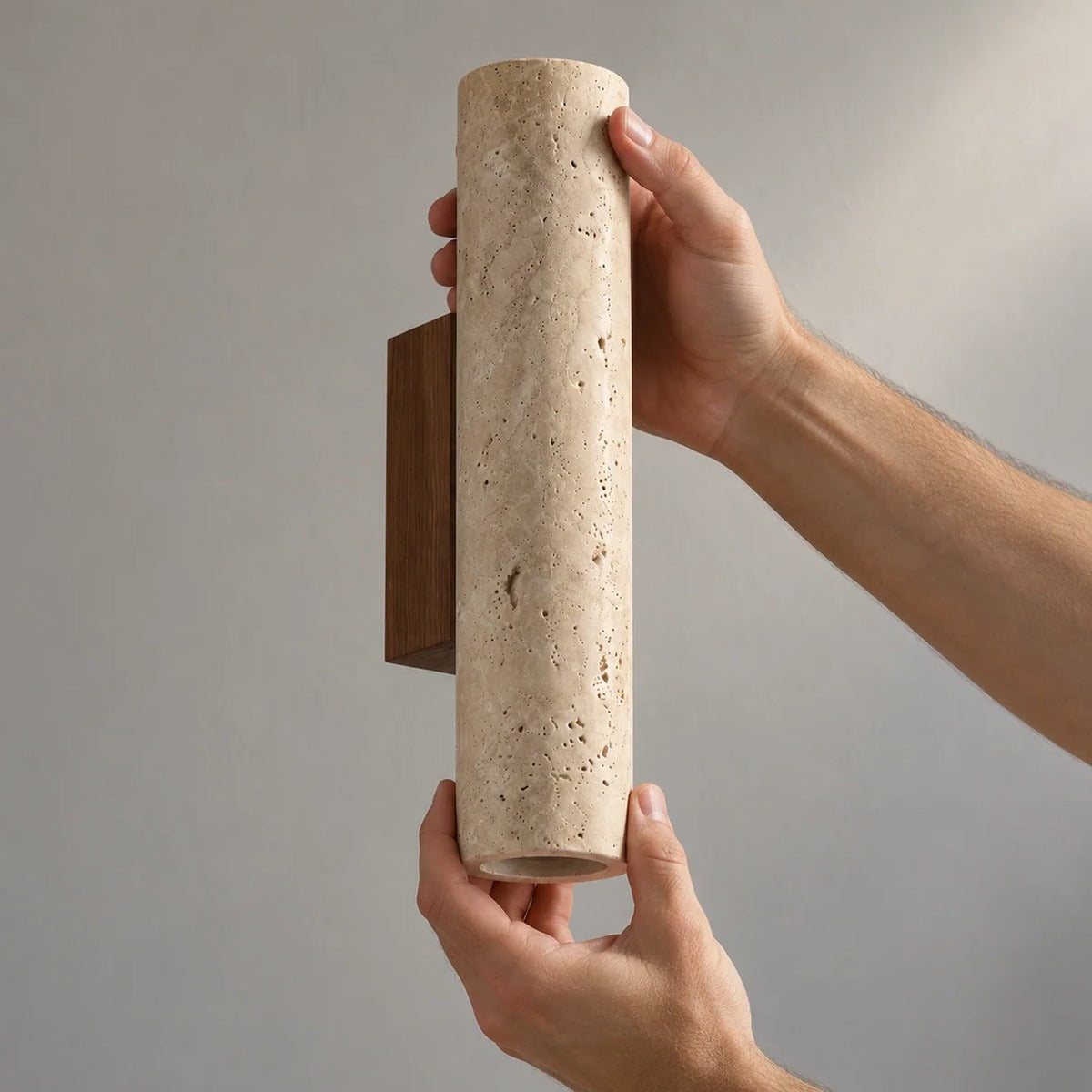 Tarra travertine wall sconce held in hand to show its size