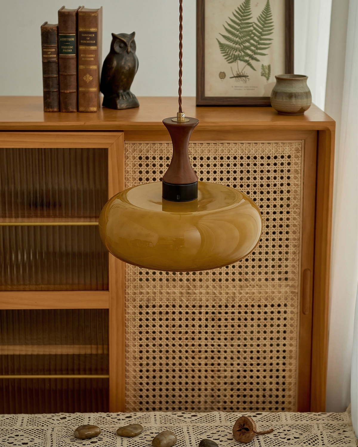 Ovia amber glass pendant above a rattan cabinet