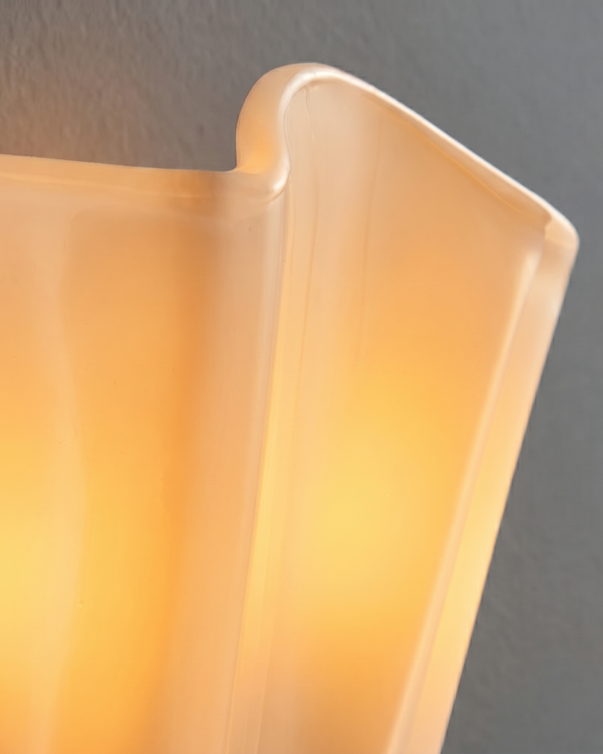Close-up of the ivory glass of the Calla wall light, lit