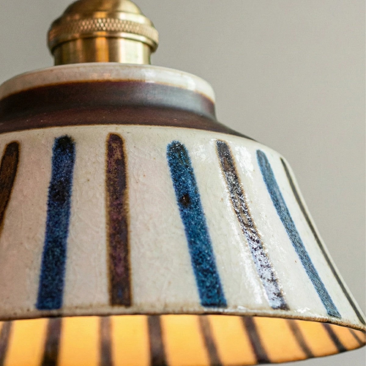 Close-up of the Hana striped ceramic shade glowing when lit