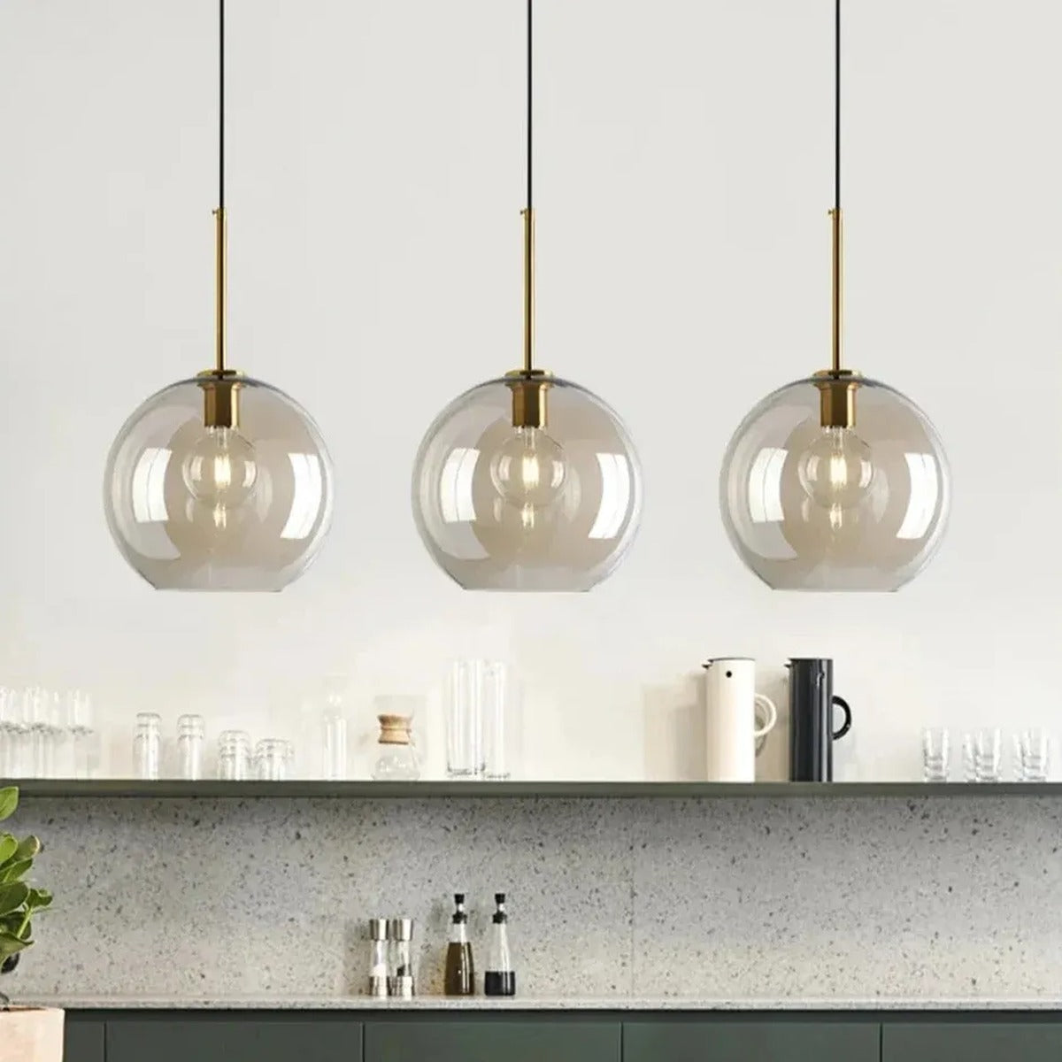 Three Ambra amber glass globe pendant lights in a kitchen with open shelving