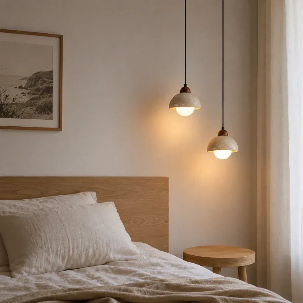 Two Cora travertine dome pendant lights glowing beside a bed