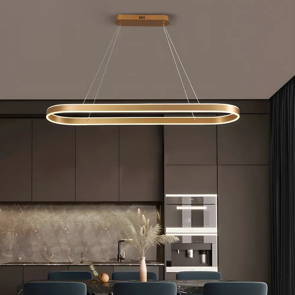 Halo oval LED pendant light in brushed gold over a kitchen island in a dark modern kitchen