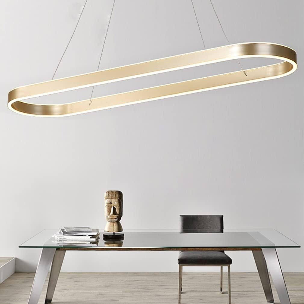 Halo oval LED pendant light in brushed gold over a glass dining table