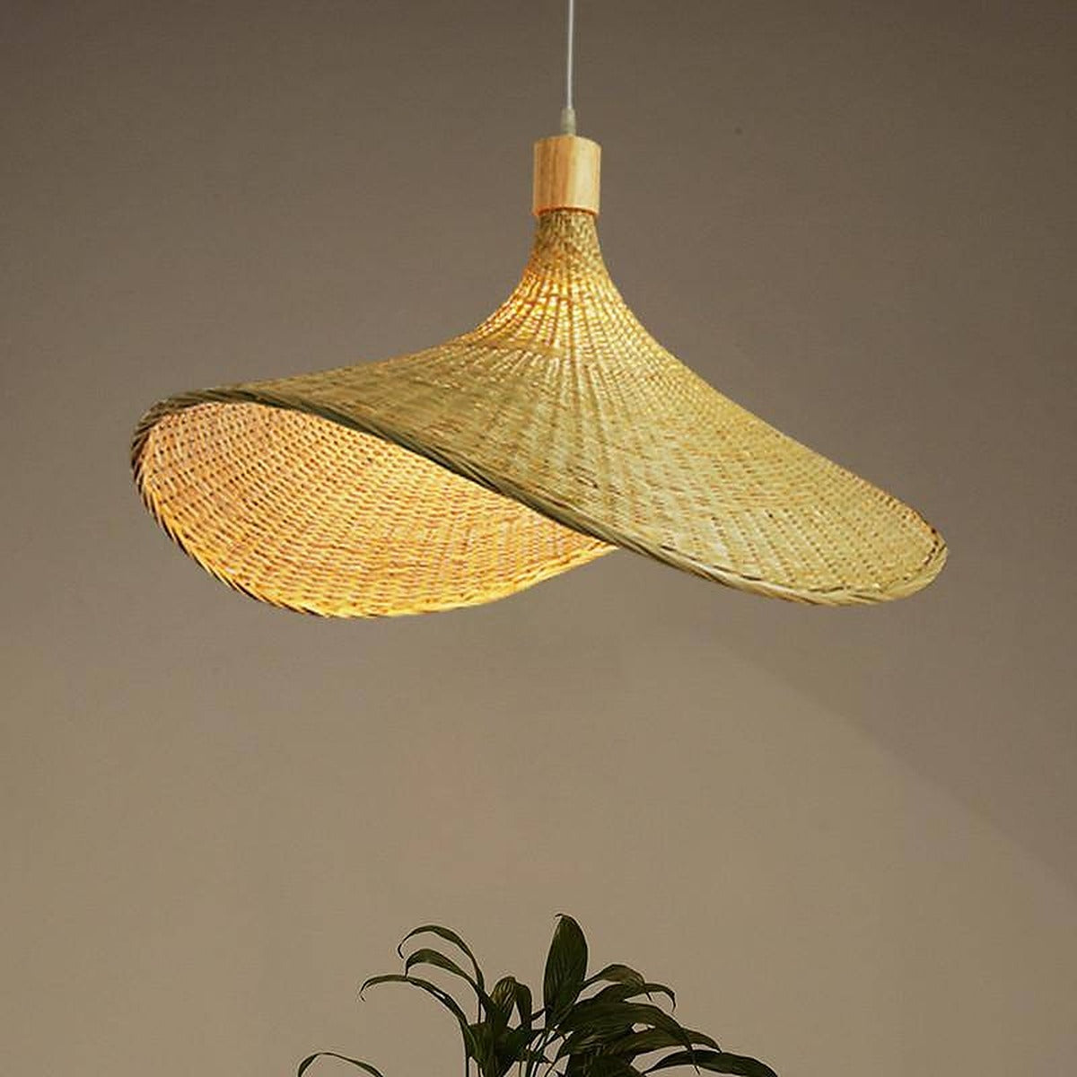 Close view of the lit Kasa bamboo hat pendant showing its open weave and wood lamp holder cover