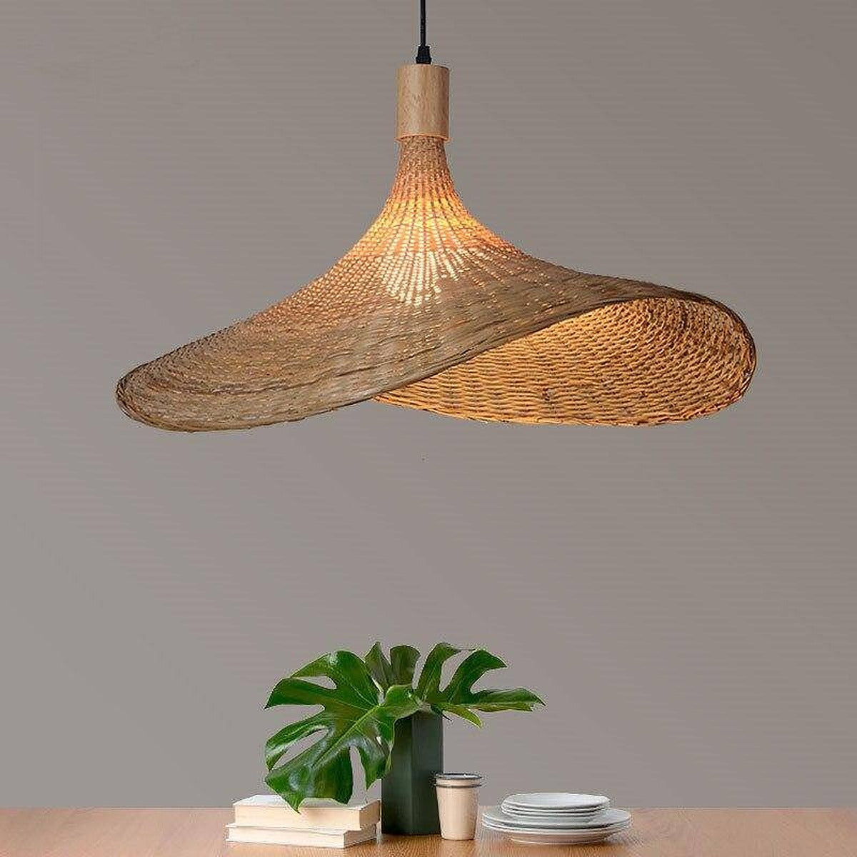 Kasa woven bamboo hat pendant with wavy brim lit over a wood table