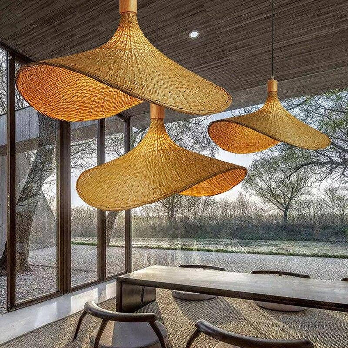 Cluster of Kasa woven bamboo hat pendant lights over a dining table by large windows