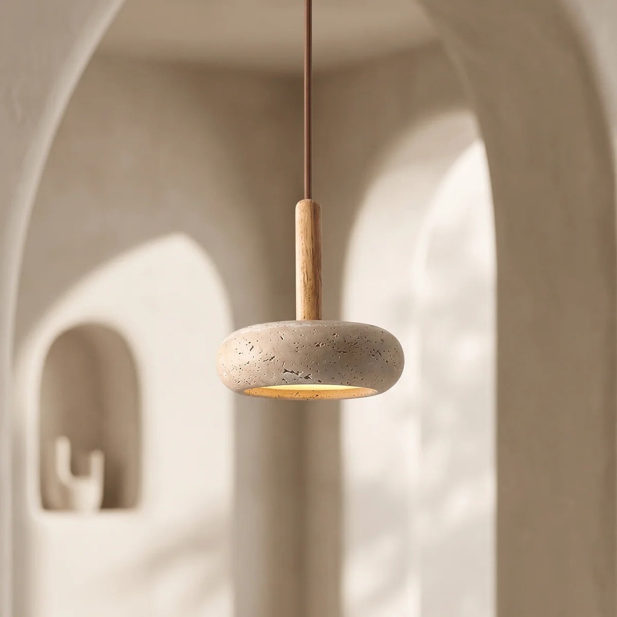 Mila travertine pebble pendant light in an arched entryway