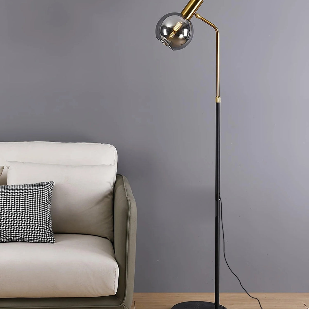 Opaline floor lamp in black with a smoked blown glass globe and marble base beside a sofa