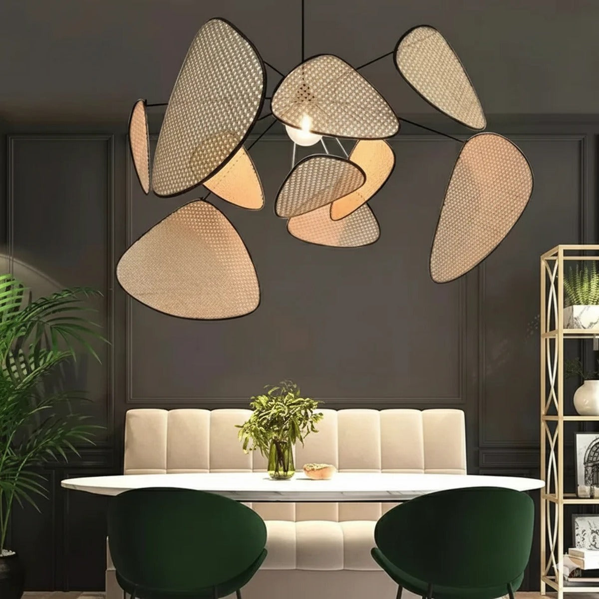 Palma woven cane petal chandelier above a dining table against a dark wall