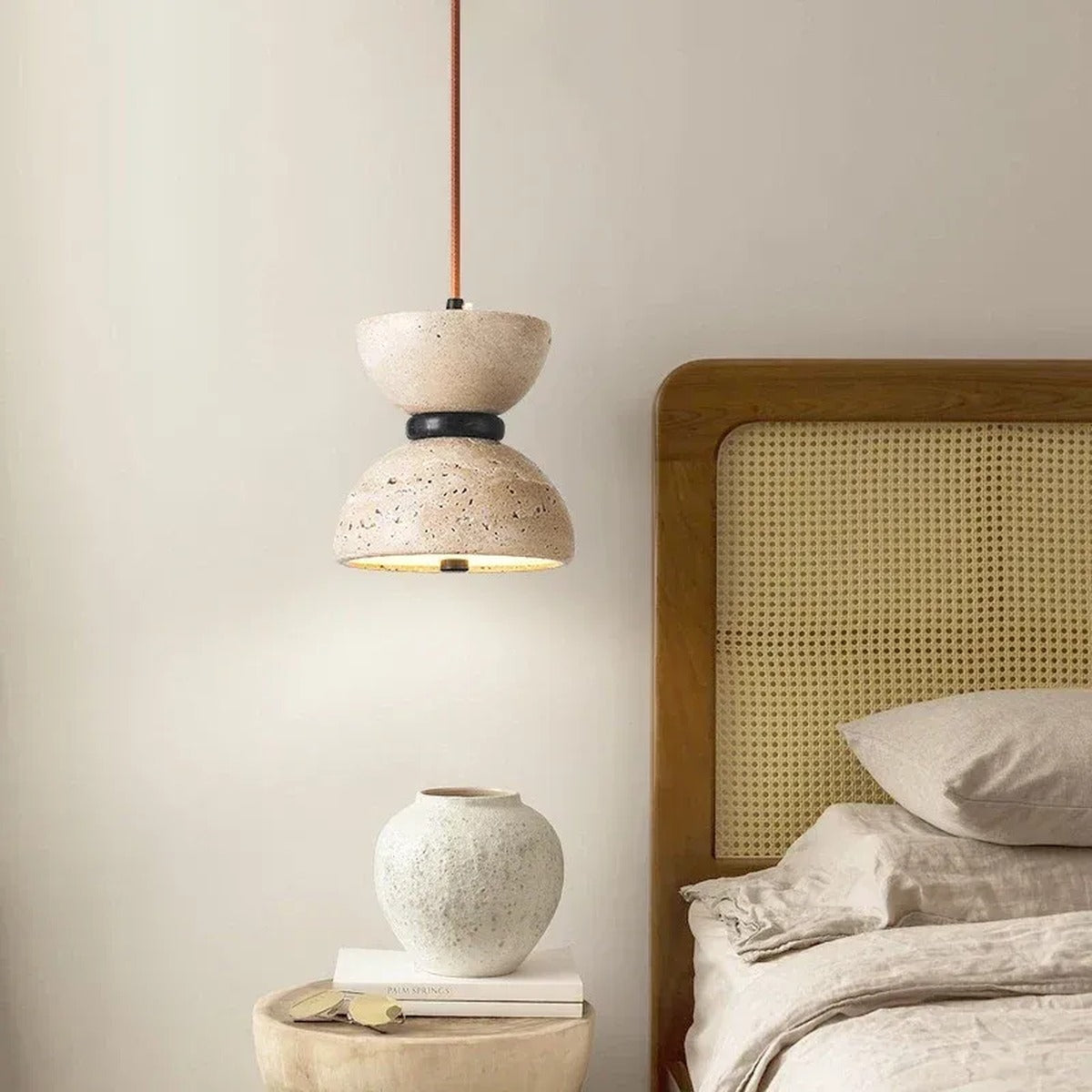Sable travertine pendant light as a bedside light next to a cane headboard