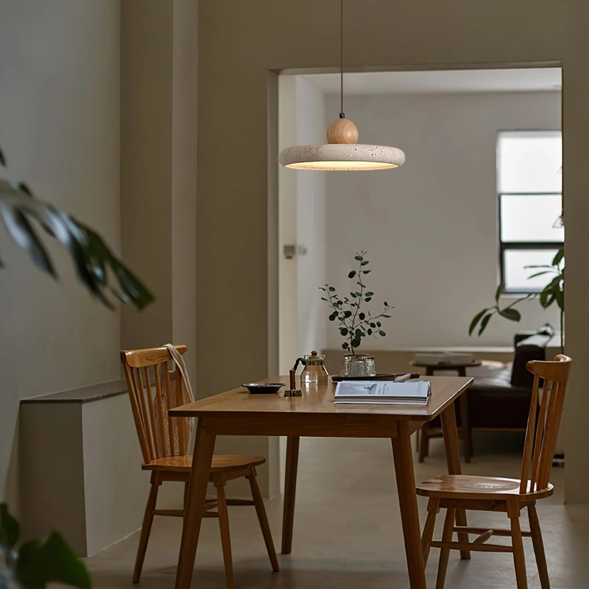 Terra travertine disc pendant light above a wood dining table