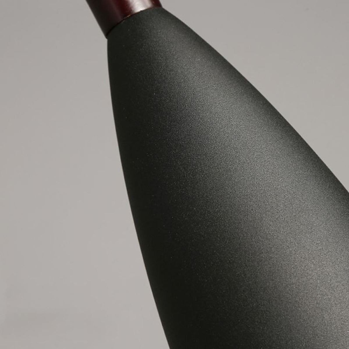 Close-up of the matte black metal shade and wood neck of the Vika pendant