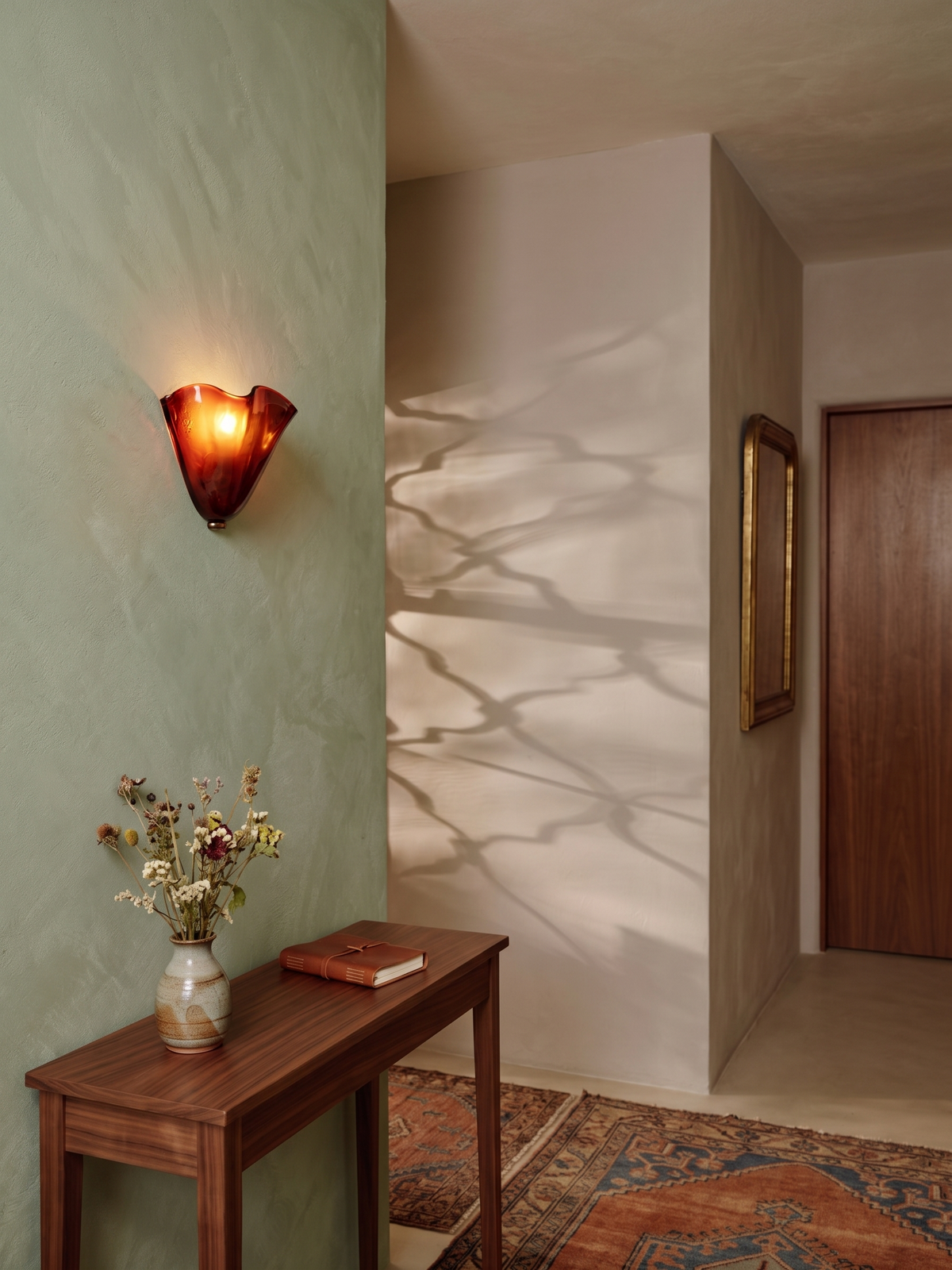 Amber brown Calla ruffled glass wall light above a console in a hallway