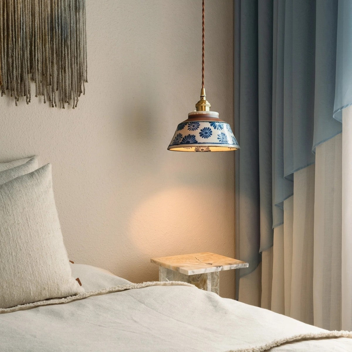 Hana ceramic pendant light in blue flower pattern beside a bed