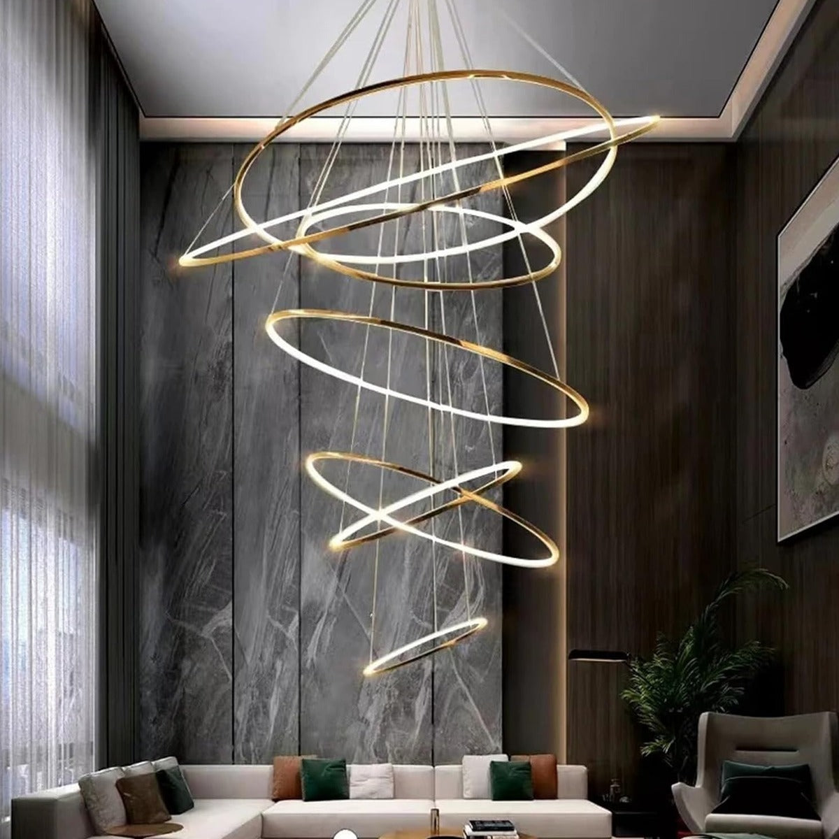 Gold Vela chandelier with 6 LED rings above a lounge with a high ceiling