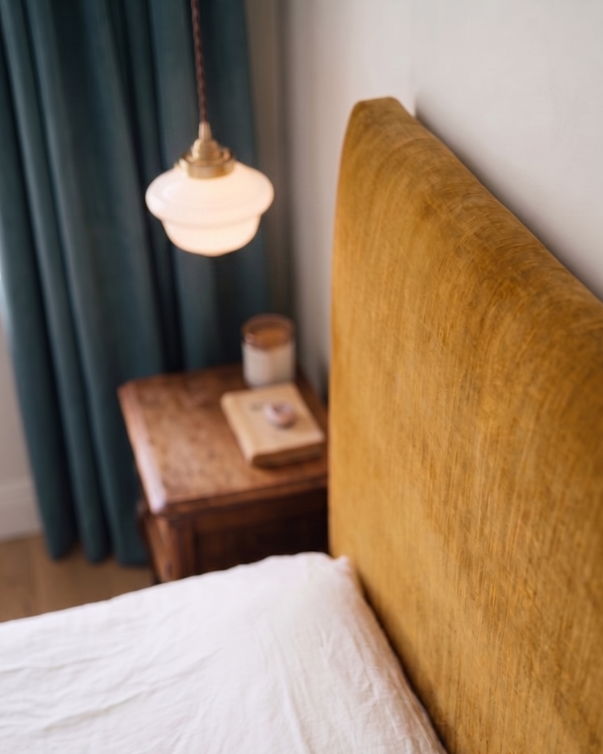Elsie pendant light hanging next to a velvet headboard