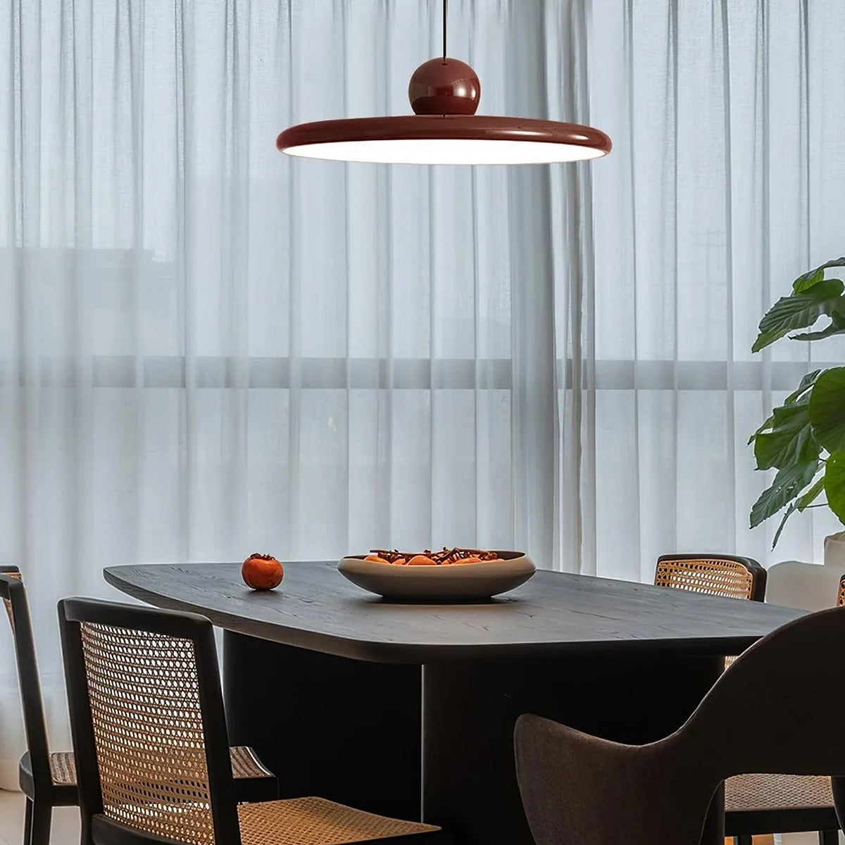 Red Juno saucer LED pendant light above a dark dining table