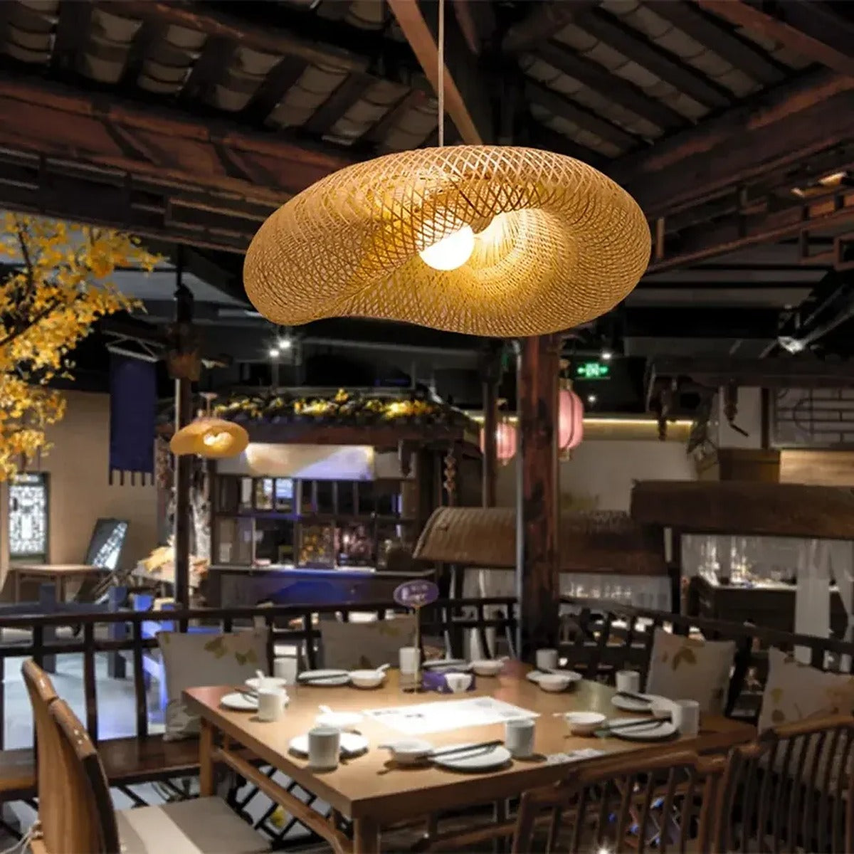 Nami bamboo wave pendant light lit over a dining table at night