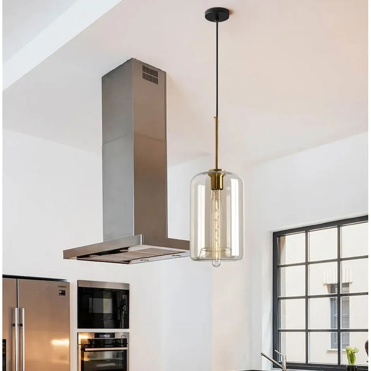 Ambra amber glass cylinder pendant light with a brass stem in a bright kitchen