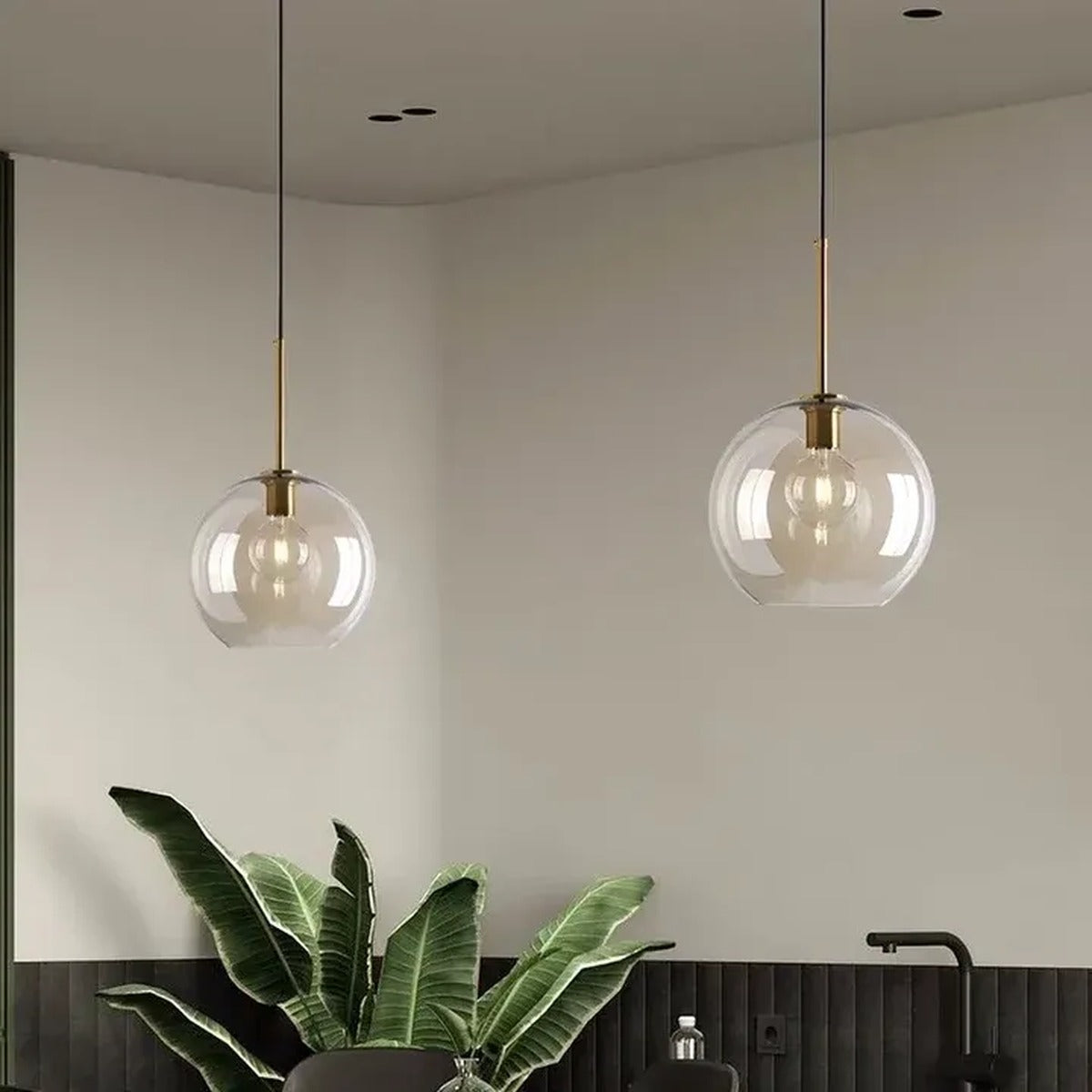 Two Ambra amber glass globe pendant lights with brass stems