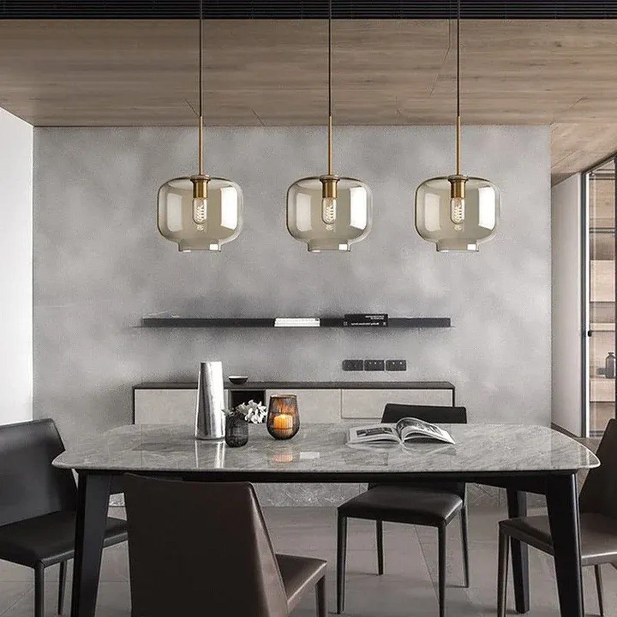 Three Ambra amber glass jar pendant lights above a marble dining table in a modern dining room