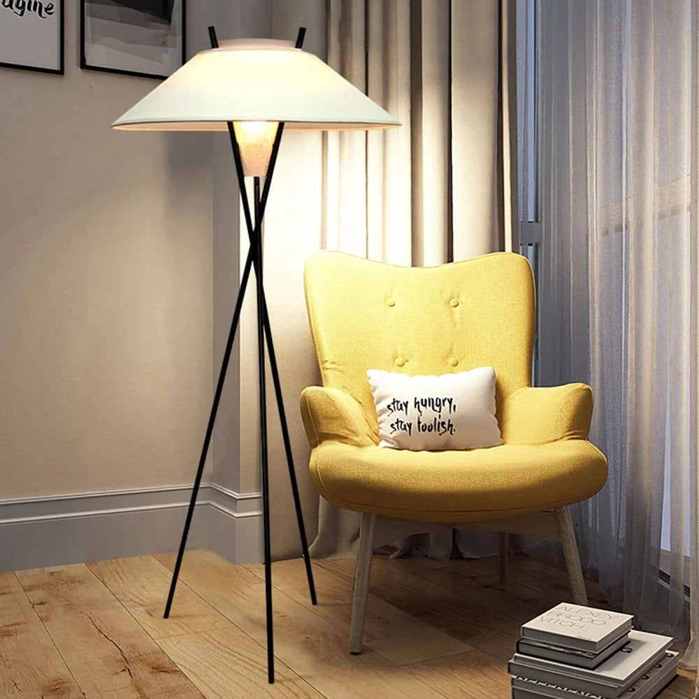 Archi black tripod floor lamp with white fabric shade lighting a reading corner