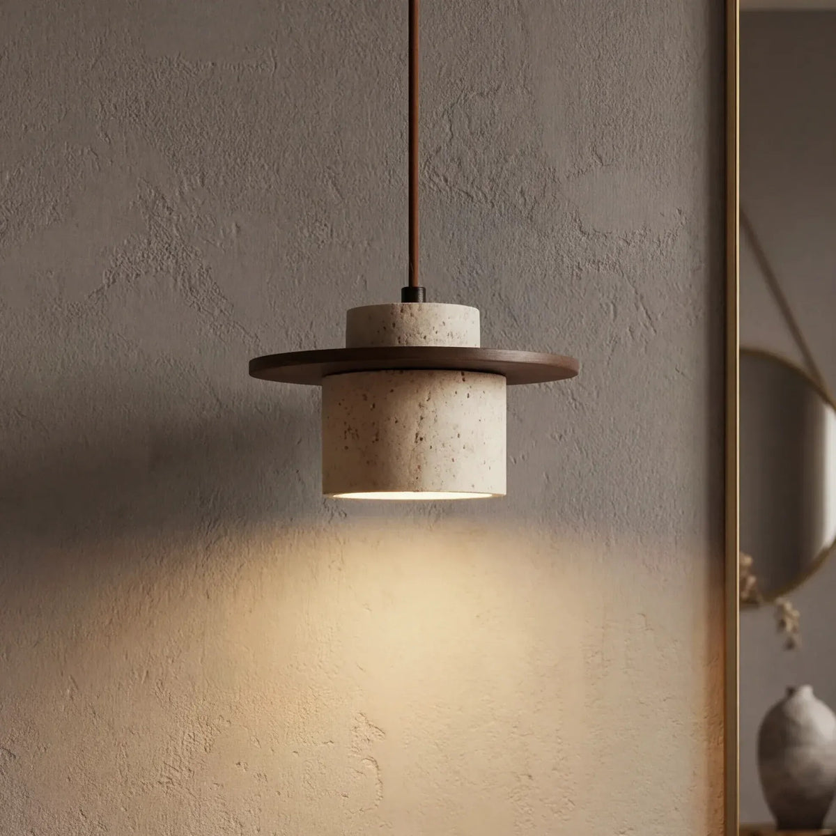 Avra travertine pendant light with walnut ring casting a warm glow on a plaster wall