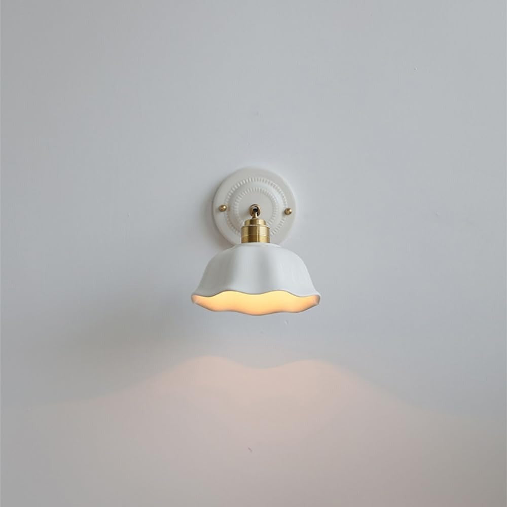 Front view of the Celia scalloped ceramic wall sconce switched on