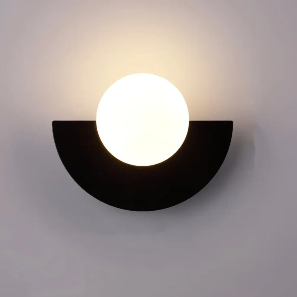 Cleo semicircle globe wall sconce in black, white glass globe with warm glow on a wall