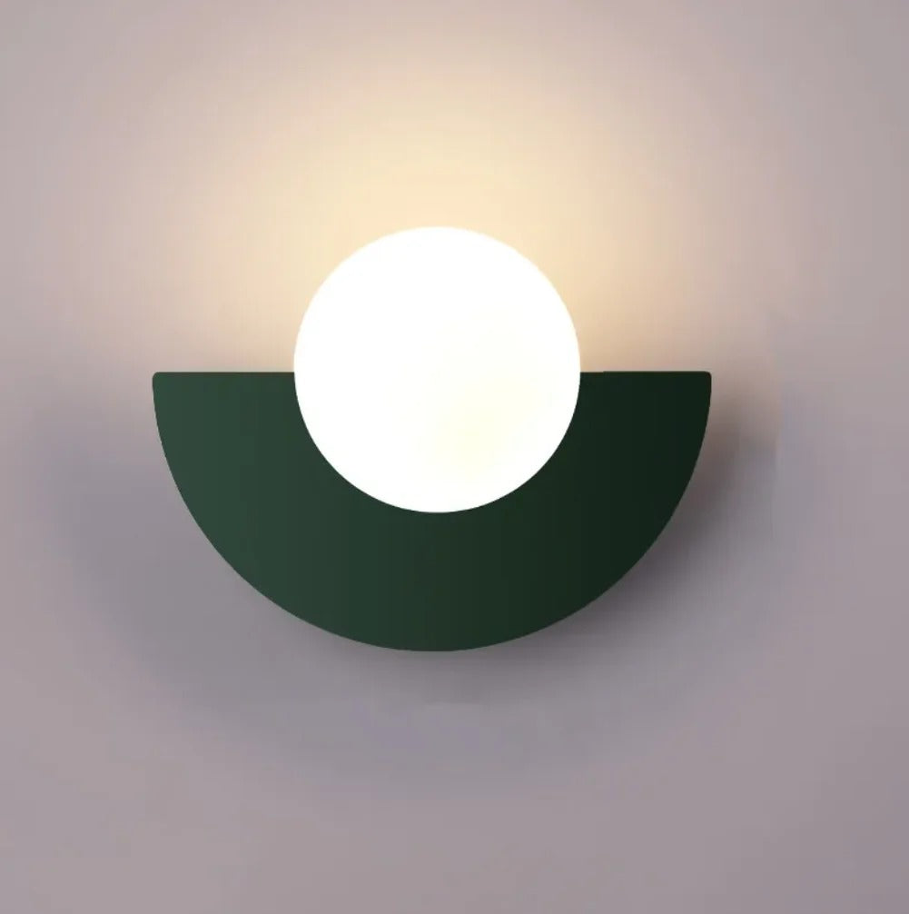 Cleo semicircle globe wall sconce in dark green, white glass globe with warm glow on a wall