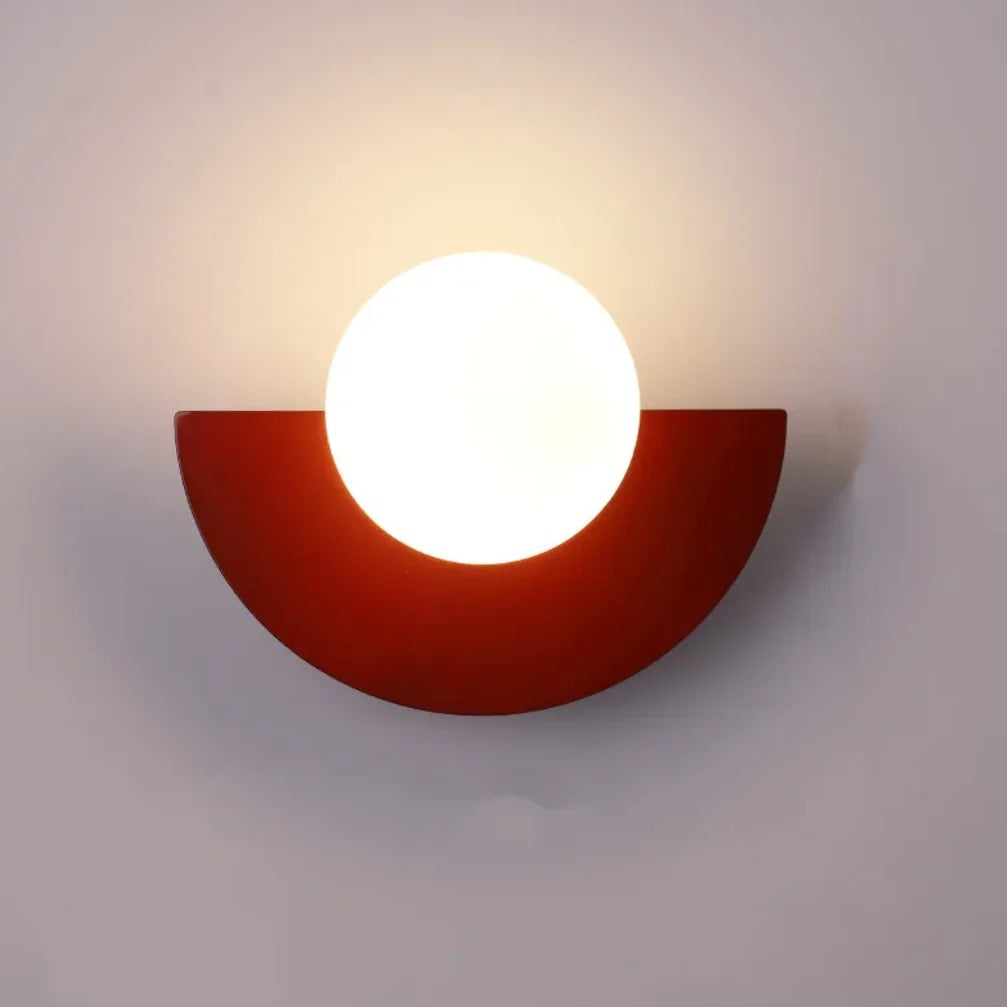 Cleo semicircle globe wall sconce in red, white glass globe with warm glow on a wall