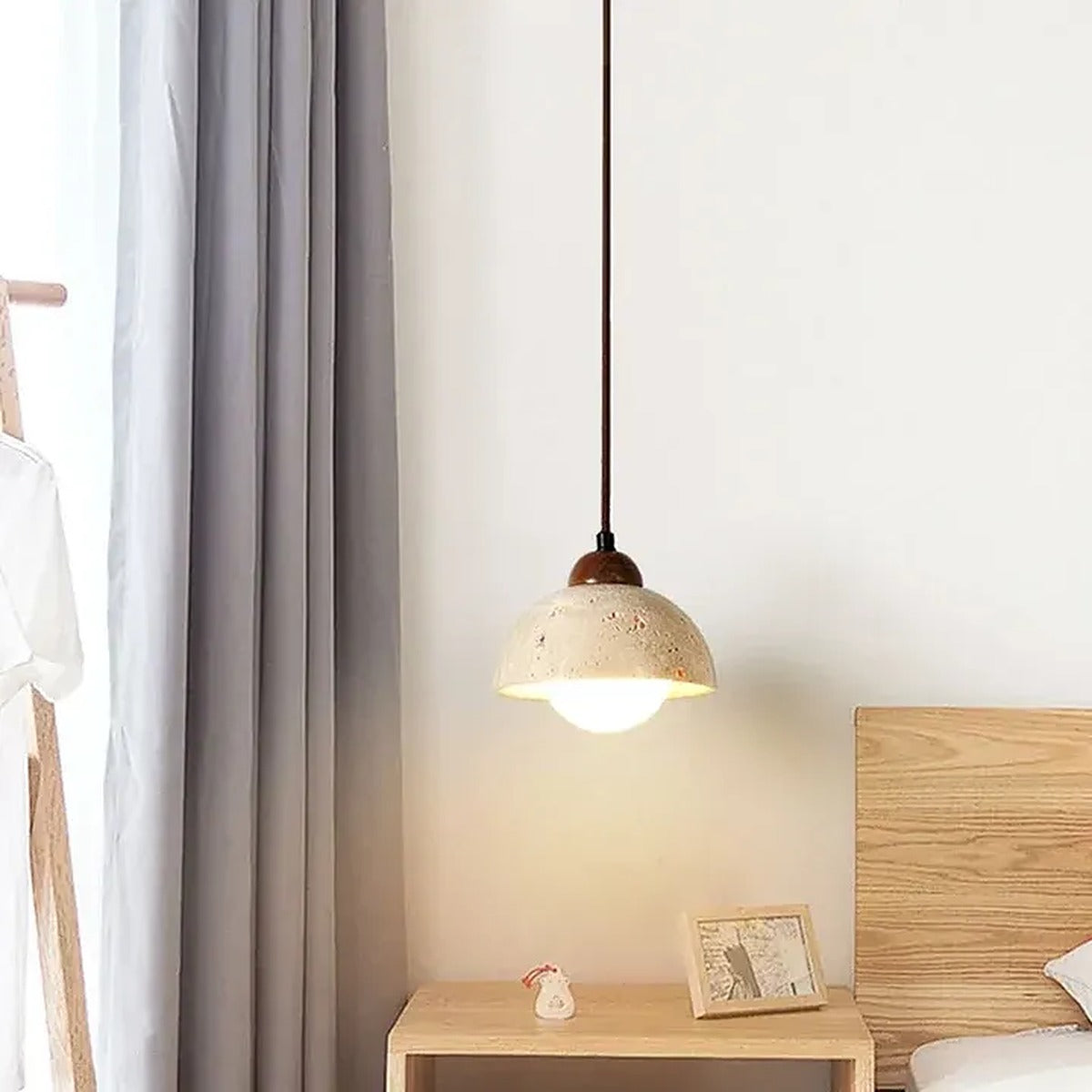 Cora travertine dome pendant light beside a bed