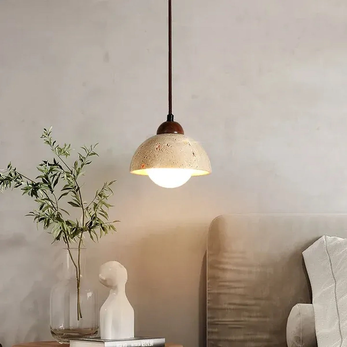 Cora travertine dome pendant light glowing in a living room