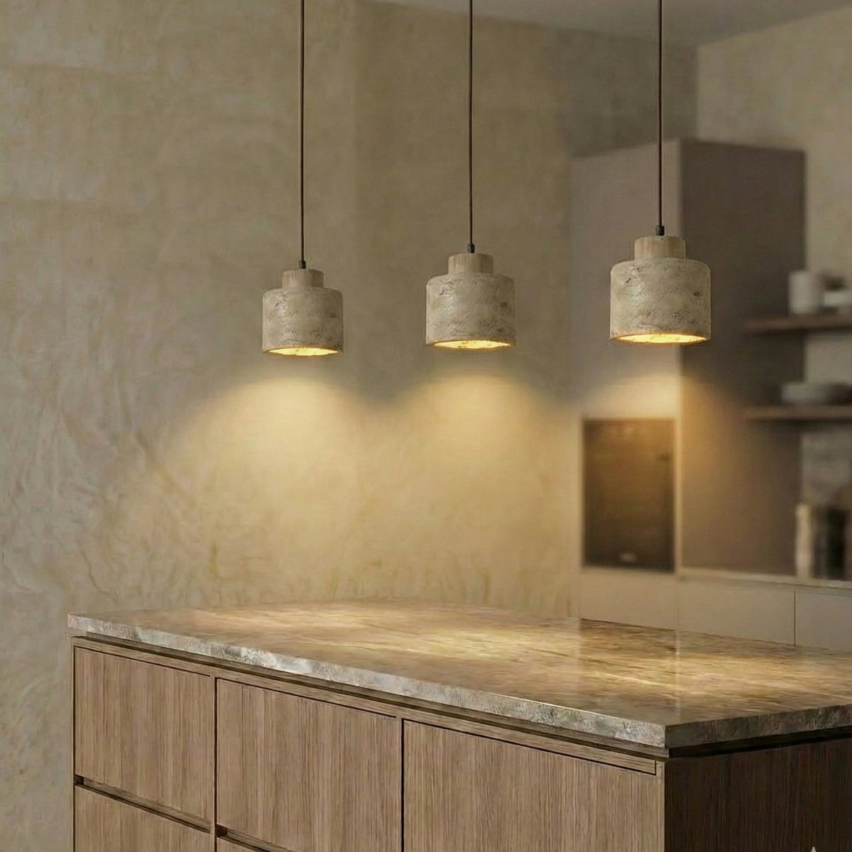 Three Cora travertine drum pendant lights above a kitchen island