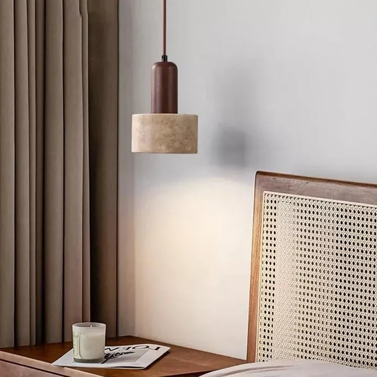 Cora travertine pendant light with a walnut neck next to a rattan headboard