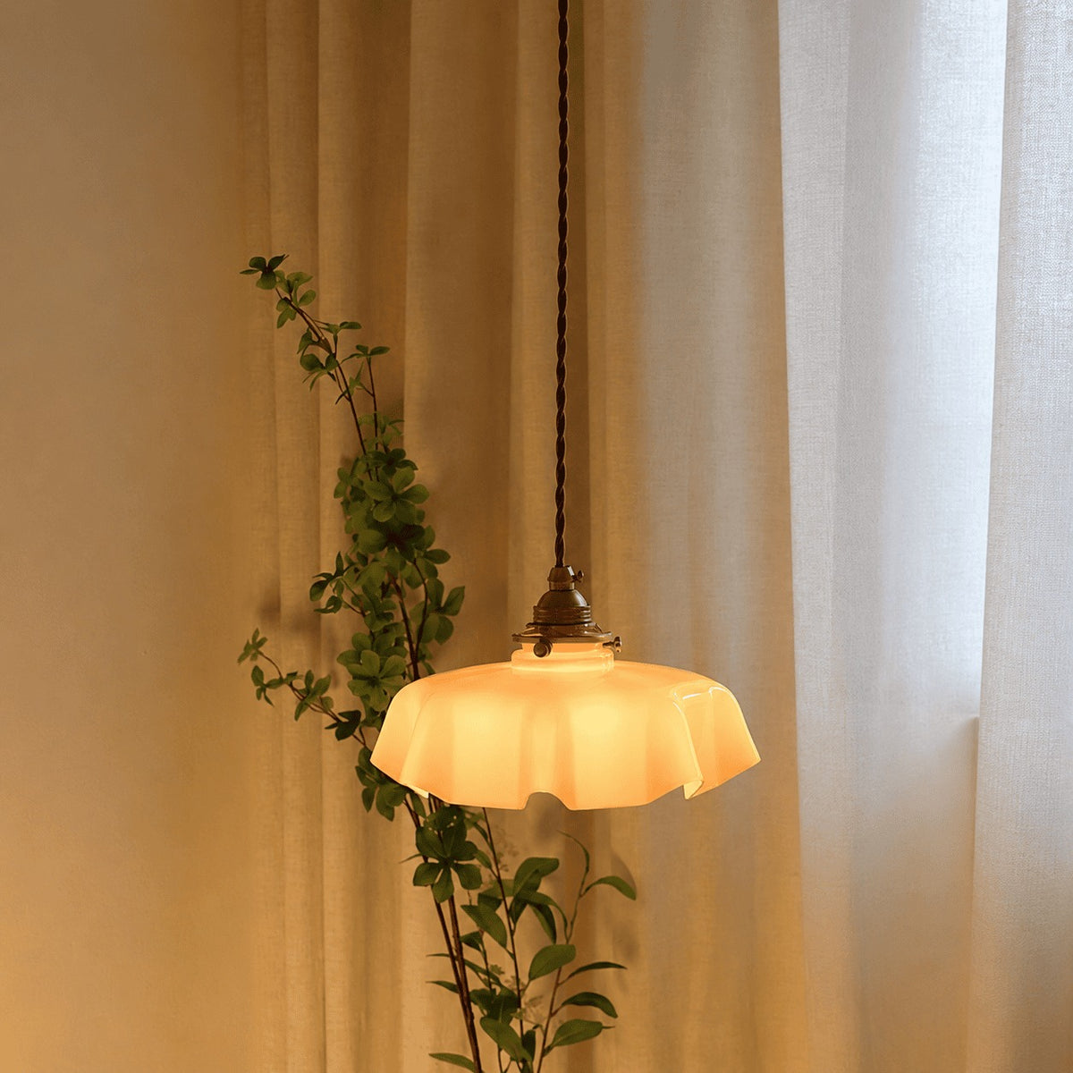 Fleur cream glass pendant light lit beside sheer curtains