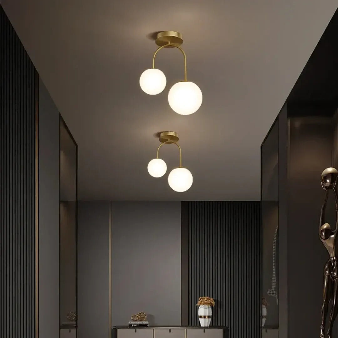 Two Gemma brass globe ceiling lights in a dark paneled hallway
