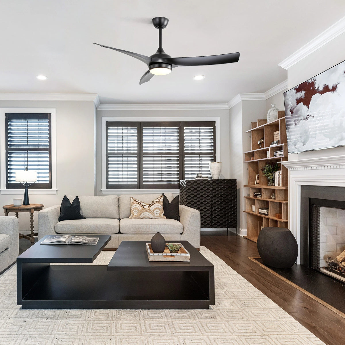 Kestrel matte black ceiling fan with LED light in a living room with fireplace
