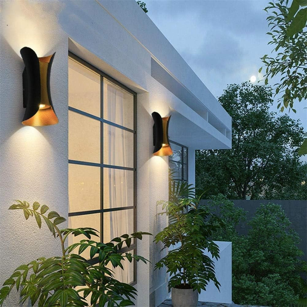 Two LEDS black and gold up and down wall sconces lighting a house exterior at dusk