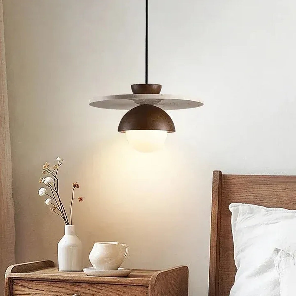Luna travertine disc pendant light glowing beside a bed