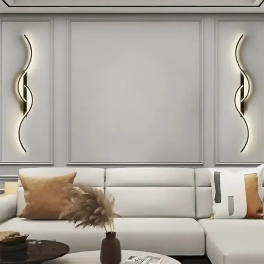 Pair of Lyra black wave LED wall sconces above a living room sofa