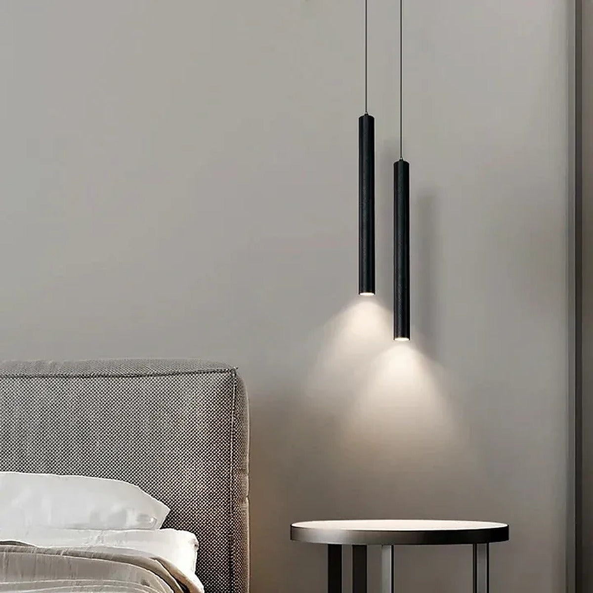 Pike black tube pendant lights above a round bedside table