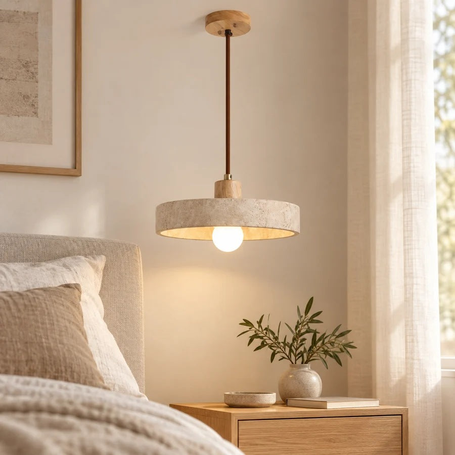 Runa travertine disc pendant light by a bedside in daylight