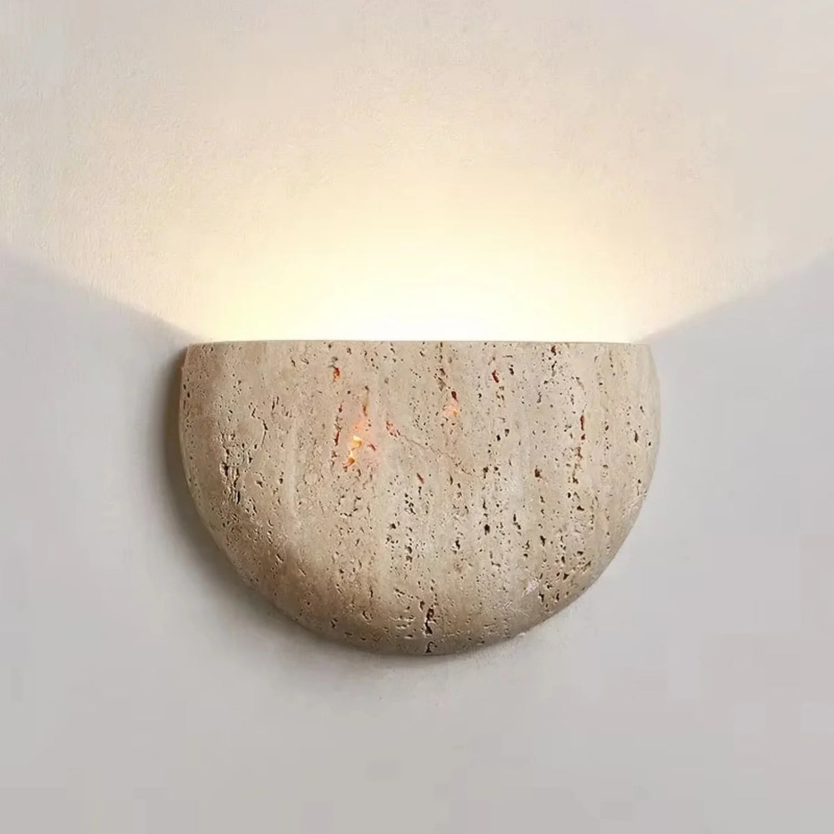 Sora travertine wall sconce casting a soft uplight halo on the wall