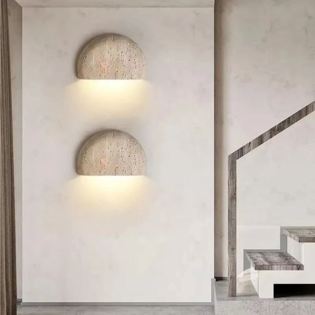 Two Sora travertine wall sconces stacked beside a staircase